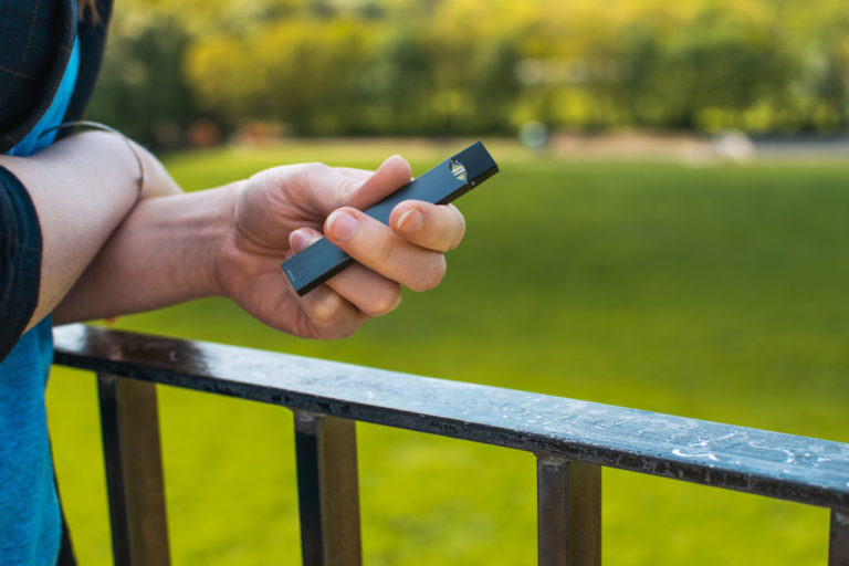 Teenager with JUUL e-cigarette in their hand